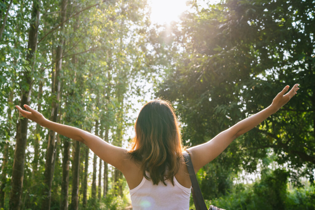 happy young asian woman traveler with backpack walking in forest